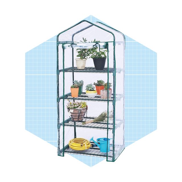 A portable greenhouse displays various potted plants and gardening tools, organized on metal shelves against a light blue background, suggesting an indoor gardening space.