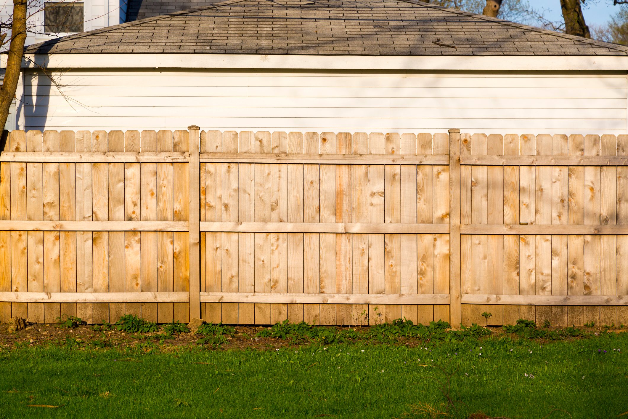 a wooden side by side fence with a green yard and a White House on the other side of the fence