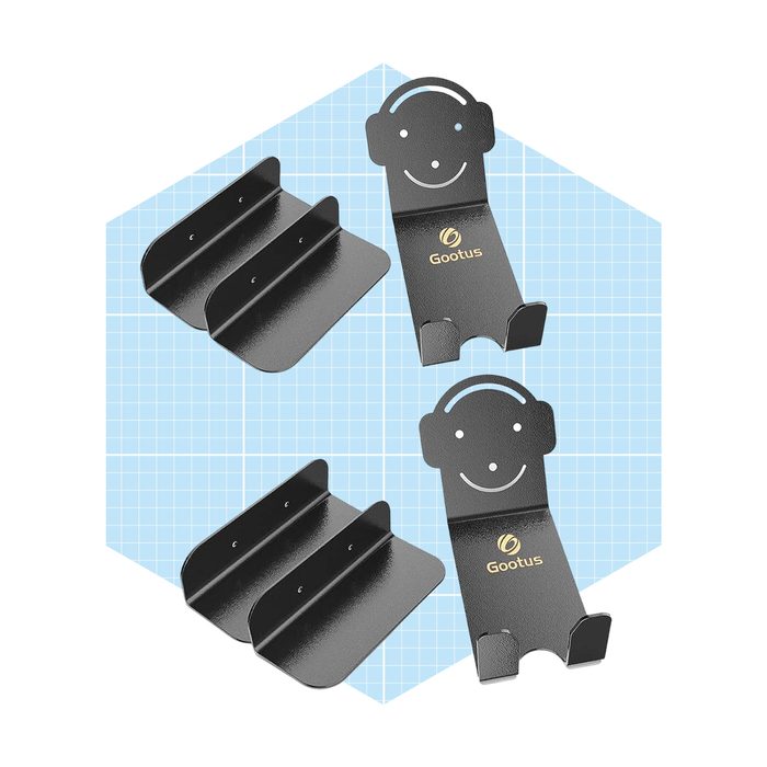 Black metal headphone stands and mounting brackets lay on a light blue grid background, designed for holding and organizing headphones.