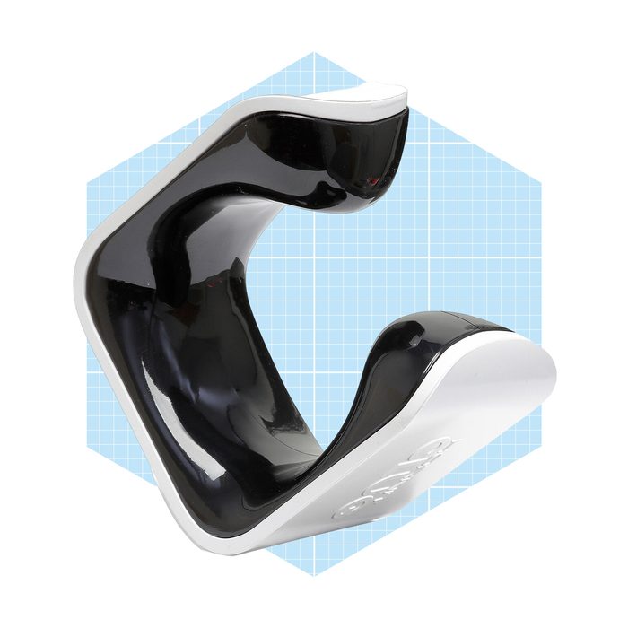 A black and white ergonomic object rests on a blue grid background, designed for comfort or support, featuring smooth curves and a modern appearance.