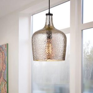A textured glass pendant light hangs from the ceiling, illuminating a bright room with large windows and soft natural light.