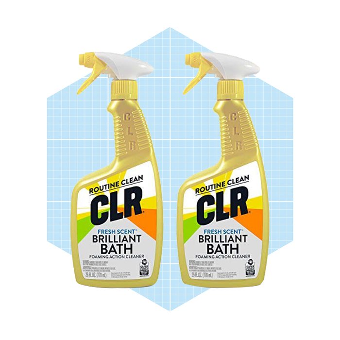 Two spray bottles of CLR Brilliant Bath cleaner are positioned side by side against a light blue grid background, showcasing their bright packaging and labeling.