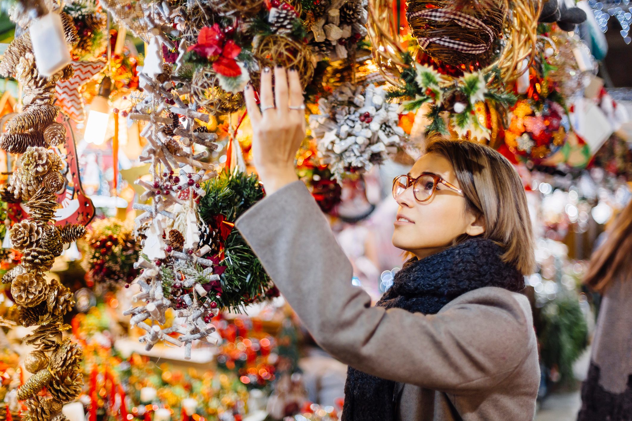 Young Woman Choosing Christmas Decoration On A Christmas Market In Barcelona, Spain