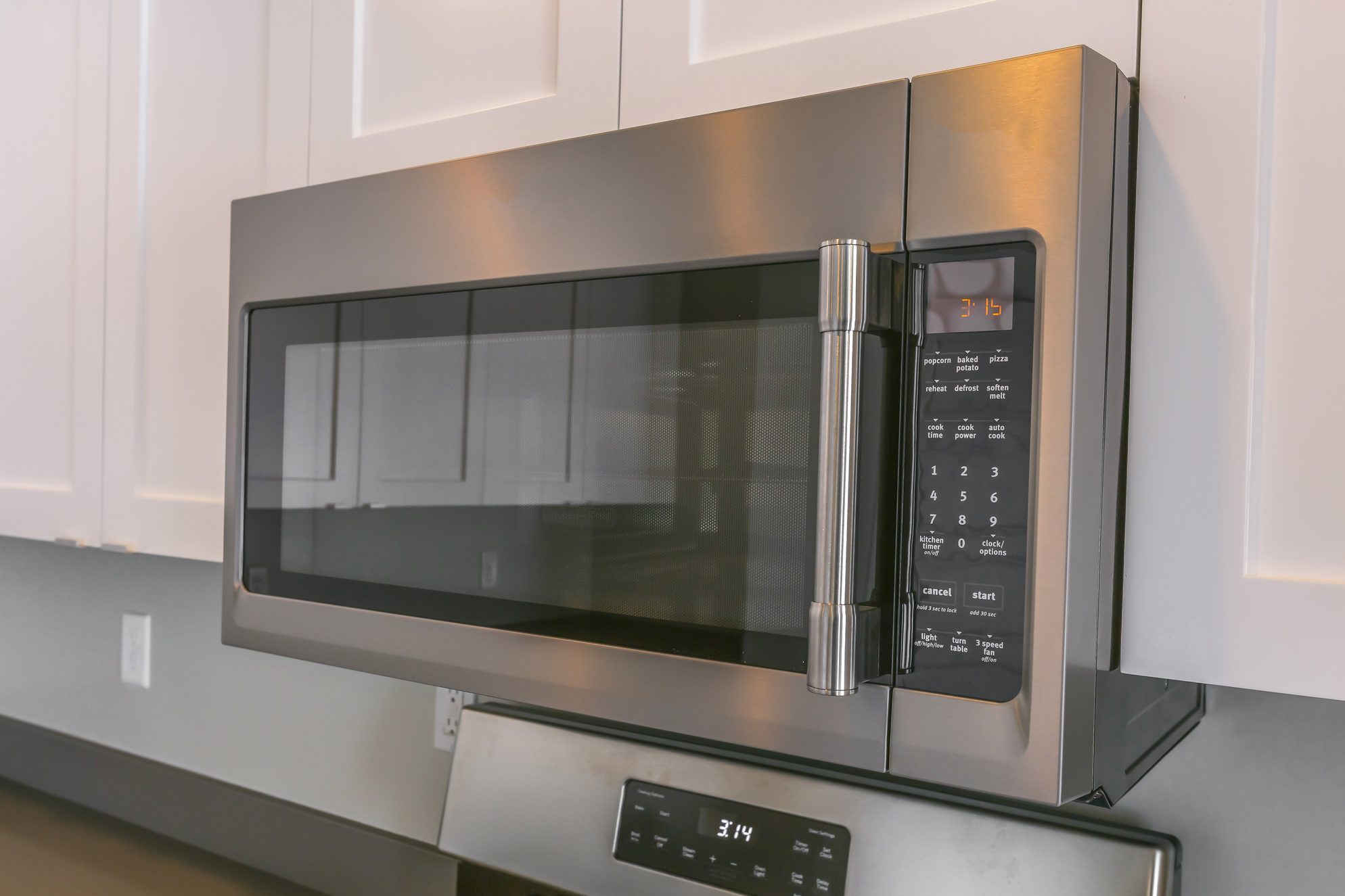 Close up of a microwave and white cabinets mounted on the wall of a kitchen