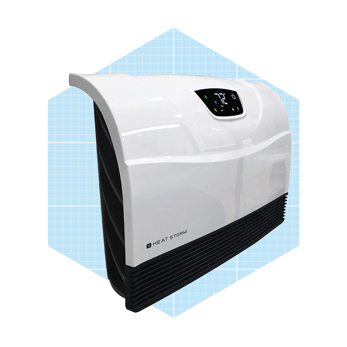 A white space heater stands upright, displaying controls on top, in front of a light blue grid background, designed for efficient indoor heating.