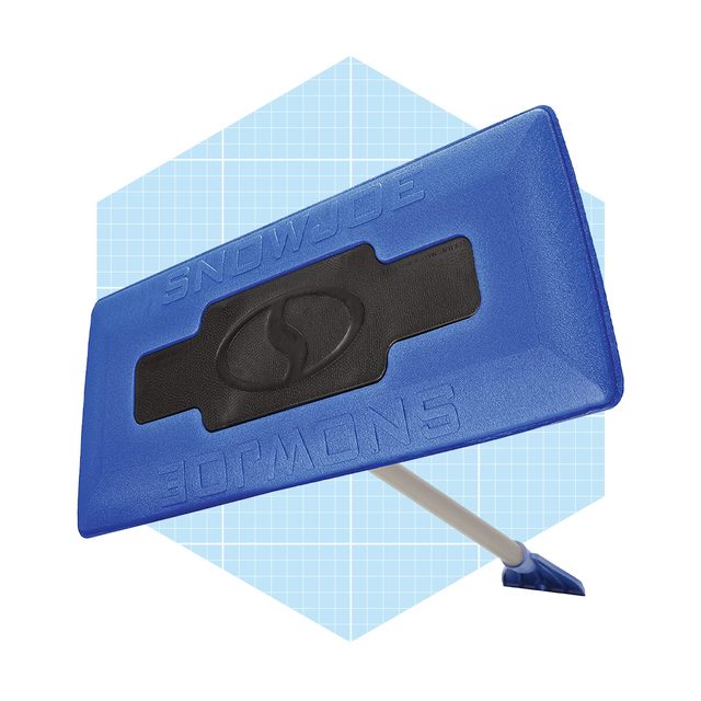 A blue snow shovel is positioned diagonally against a light blue, grid-patterned background, emphasizing its flat blade and sturdy handle for snow removal.