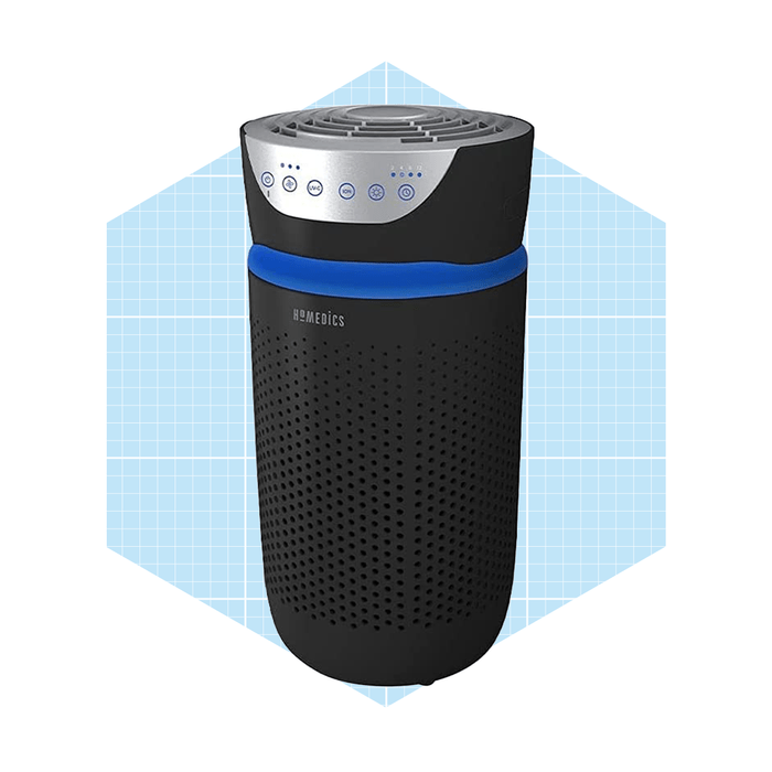 A cylindrical air purifier is operating, featuring a metallic top with buttons and a blue accent, set against a light blue geometric background.