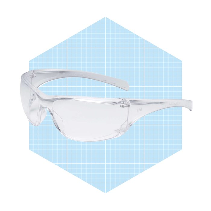 Clear safety glasses rest on a light blue, grid-patterned background, designed to protect eyes while working in various environments.