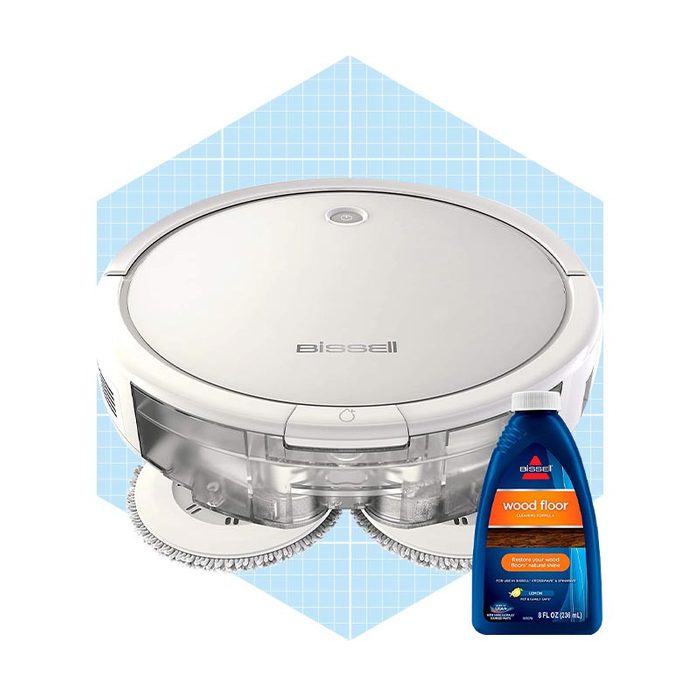 A circular Bissell robotic cleaner and a bottle of wood floor cleaner rest against a light blue geometric background, suggesting a home cleaning context.
