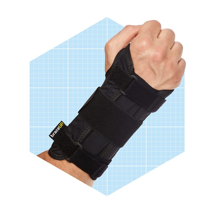 A black wrist brace secures a hand in a fist position, set against a light blue graph paper background.