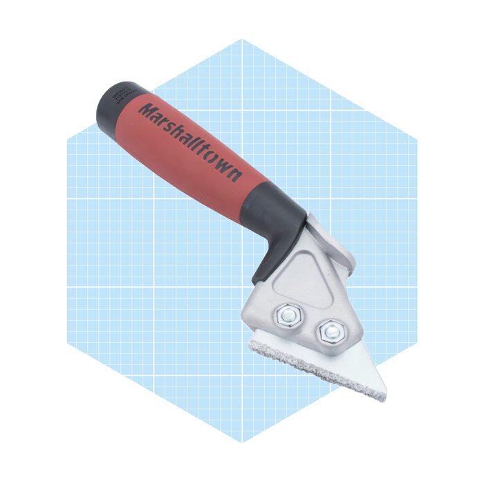 A metal scraping tool with a red handle is positioned against a light blue grid background, designed for smoothing or removing materials.