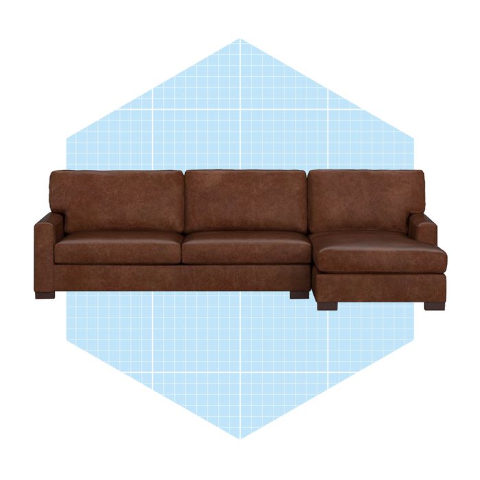 A brown sectional sofa rests on a light blue grid-patterned background, offering a spacious seating area with wide arms and cushions.