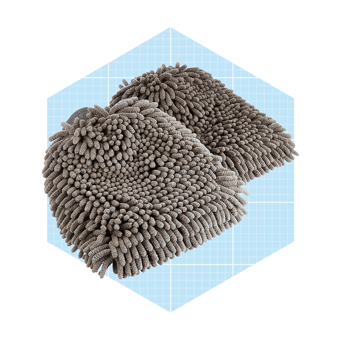 Soft, textured slippers rest on a light blue hexagonal background, featuring a unique, fuzzy design ideal for comfort and warmth.