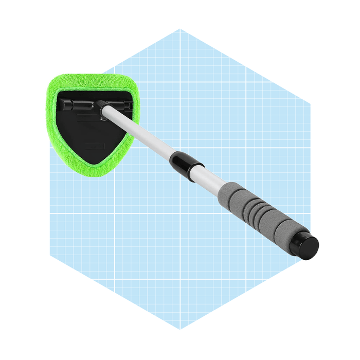 A triangular mop head with a green microfiber cover is positioned on a silver extendable handle, set against a light blue grid background.