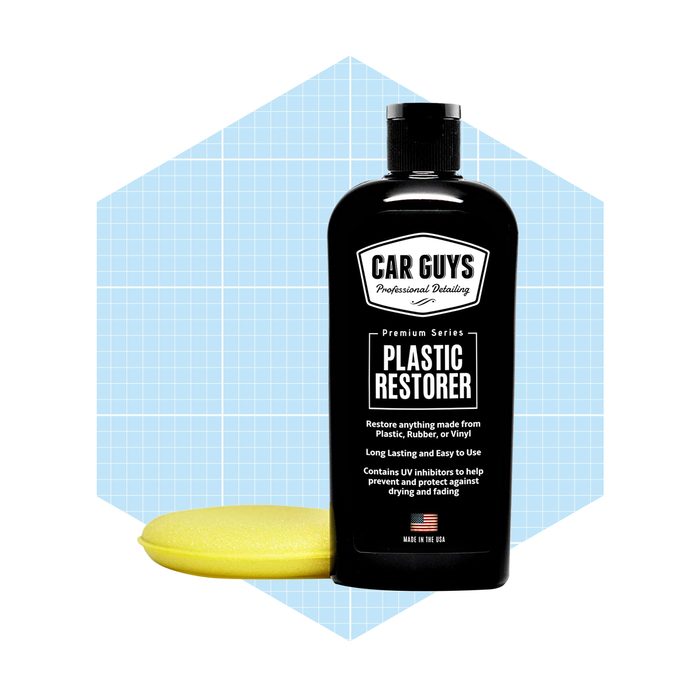 A bottle of black plastic restorer stands beside a yellow applicator sponge against a pastel blue geometric background, highlighting the product