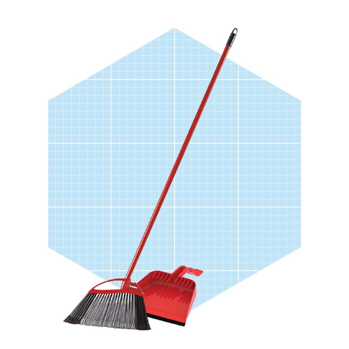A red broom and dustpan are positioned together, ready for cleaning, against a light blue grid-patterned background.