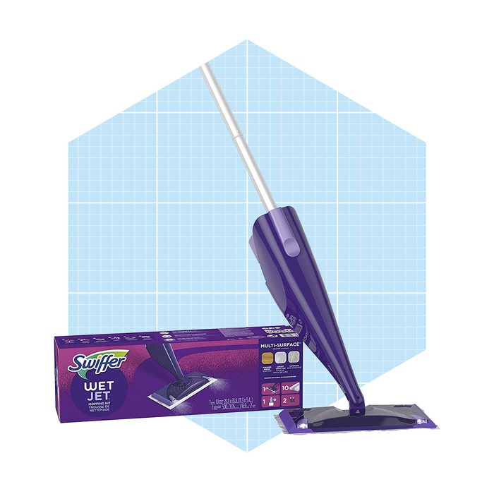 A purple cleaning device stands upright on its packaging, ready for use, set against a light blue geometric background.