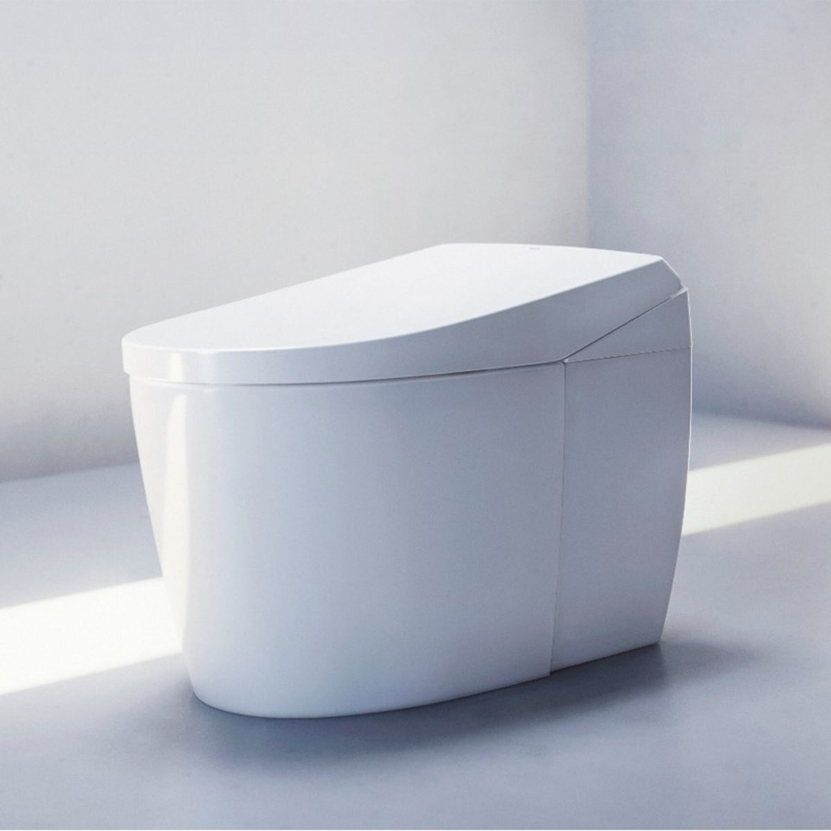 A sleek, modern toilet sits in a bright, minimally designed restroom, reflecting soft light on its smooth, white surface.