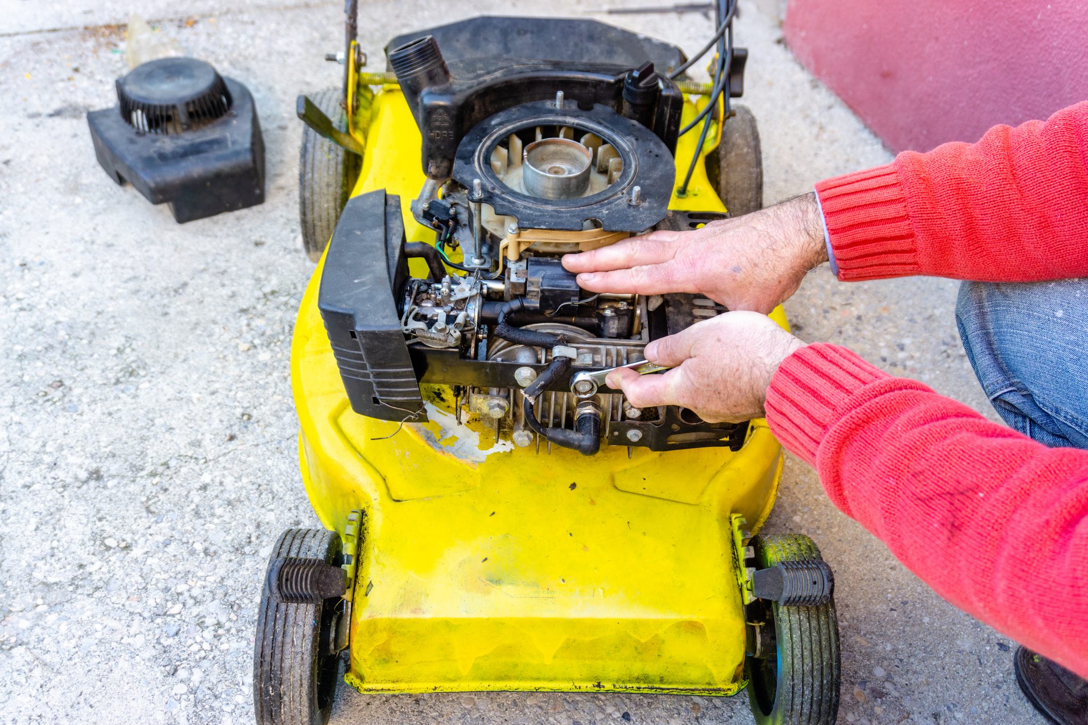 hand of man repairing old grass cutter with tools on cement floor. Repairing lawn mower engine.