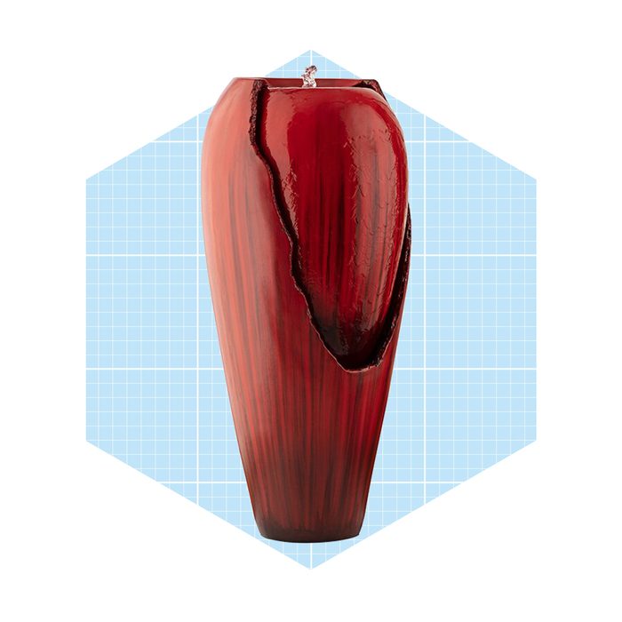 A tall, reddish vase features a cracked design, with water flowing from the top, set against a light blue grid background.