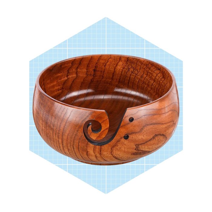 A wooden bowl with a decorative design resembling a swirl and small dots. It sits against a light blue grid background.