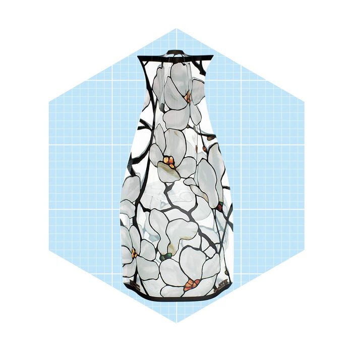 A vase with a floral design holds a transparent liquid, set against a light blue grid background, highlighting its artistic features.