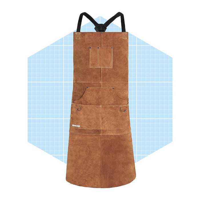 A brown leather apron hangs vertically, featuring multiple pockets and clips. It stands against a light blue grid-patterned background, creating a clean visual contrast.