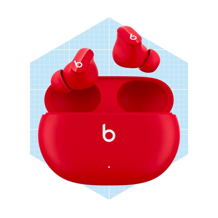 Red wireless earbuds are positioned above an open charging case. A light blue grid background adds context to the vivid display.