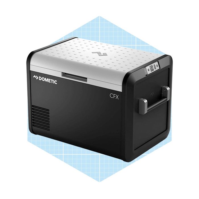 A portable cooler sits on a flat surface, designed for keeping items cold, with a sleek black and silver exterior, featuring control panels and a sturdy handle.