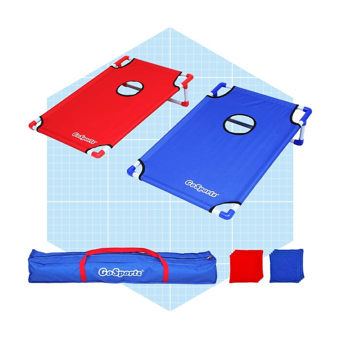 Two foldable cots, one red and one blue, are positioned side by side. A blue carrying bag and small red and blue accessories are nearby.