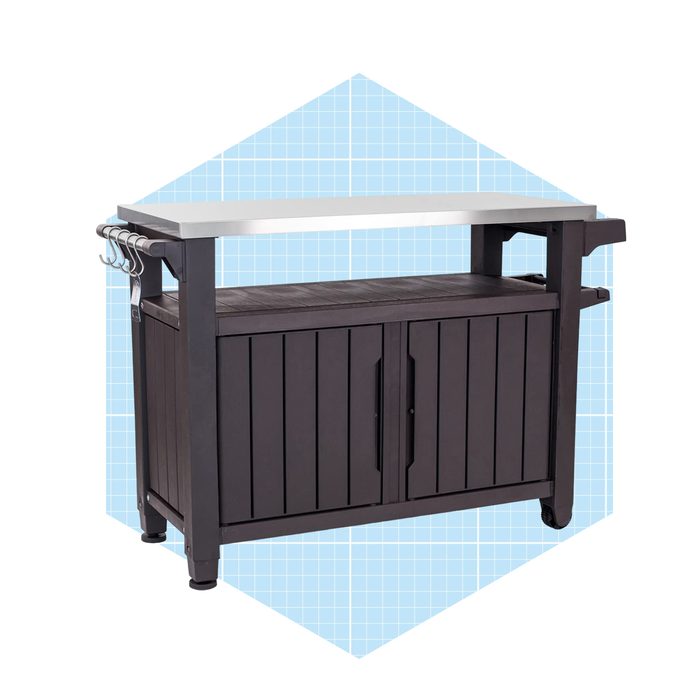 A dark wooden kitchen cart with a stainless steel top is displayed against a light blue grid background, featuring hooks on one side for utensils.