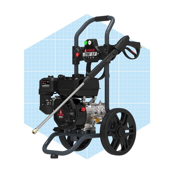 A pressure washer stands upright on two wheels, equipped with a spray gun and engine, intended for cleaning surfaces, set against a light blue grid background.