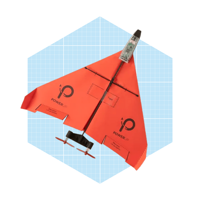A bright orange paper airplane with a propeller is positioned flat on a light blue grid background, showcasing its design and features.