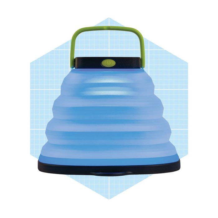 A blue collapsible lantern sits upright with a green handle, designed for portable lighting. It’s featured against a light grid background.