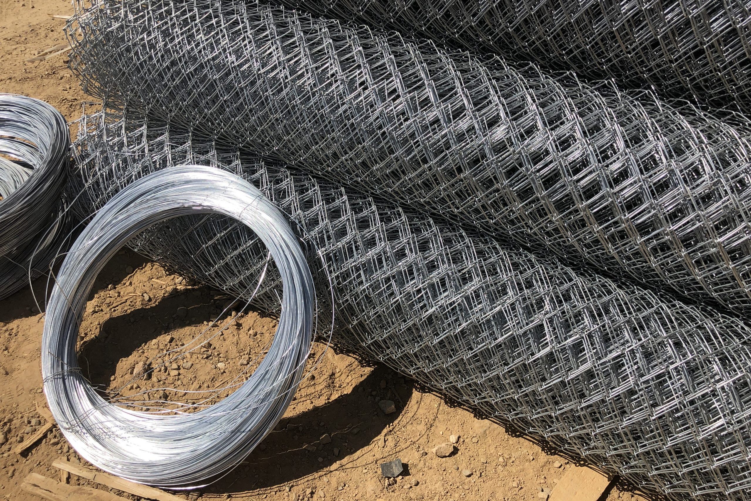 Metal mesh netting rolled into rolls and coils of steel wire. Rolled chain-link fence
