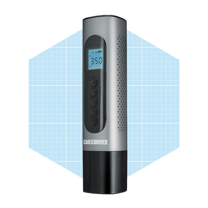 A cylindrical digital tire inflator stands upright, displaying a pressure gauge and control buttons, set against a light blue geometric background.