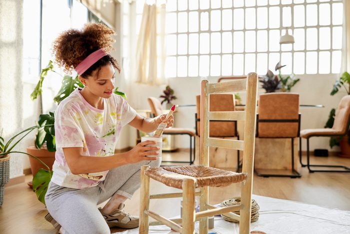 Smiling Young Female Painting Chair At Home