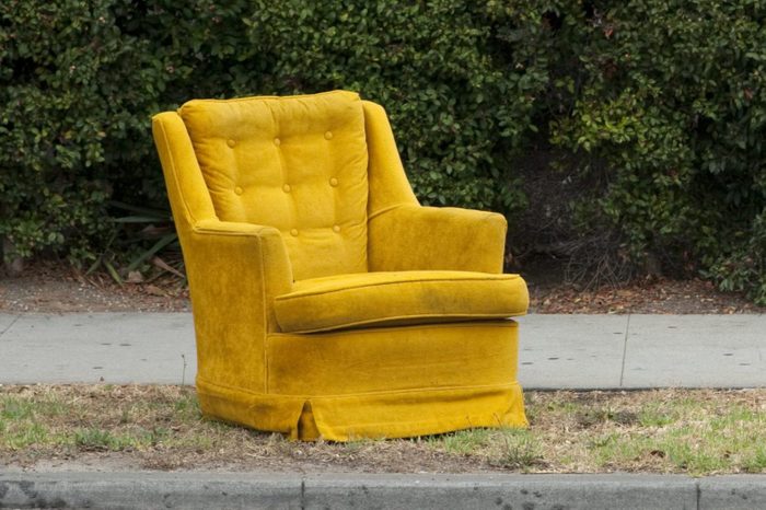 Mustard chair on a curb near a hedge