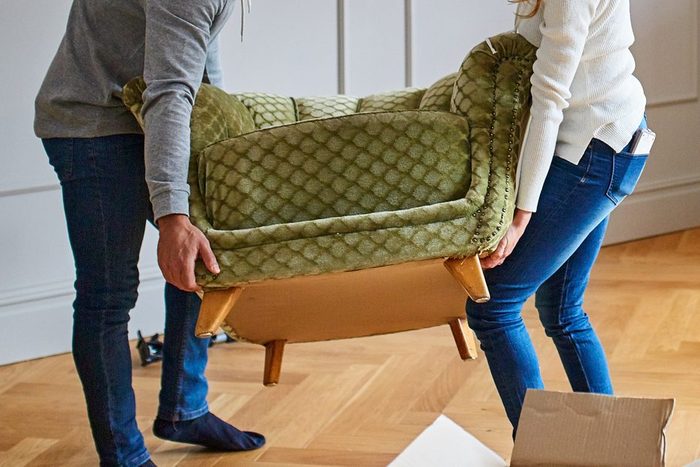 two people moving an old green chair