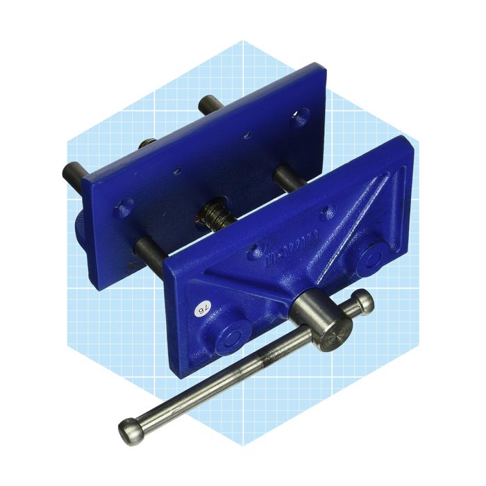 A blue jaw vise holds objects firmly in place, featuring metal rods for adjustment, set against a light grid-patterned background.
