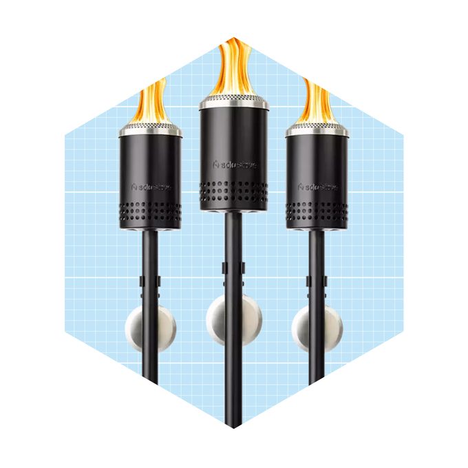 Three torch-like devices emit flames on top, mounted on poles. They stand against a light blue grid background, suggesting a decorative or outdoor lighting context.