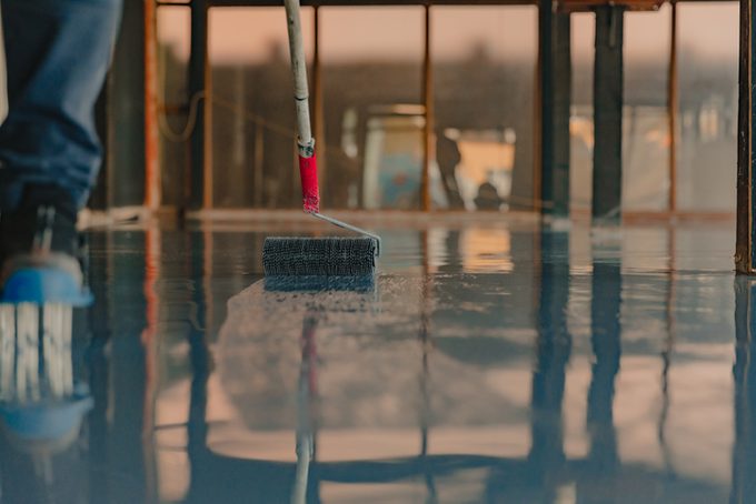 The worker applies gray epoxy resin to the new floor
