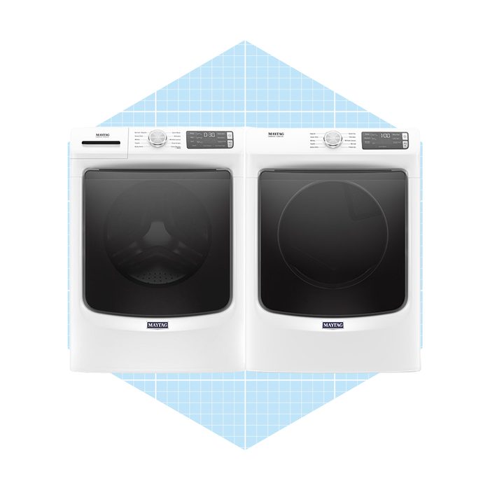 A white washing machine and dryer set displays dark tinted doors, positioned side by side against a light blue grid-patterned background.