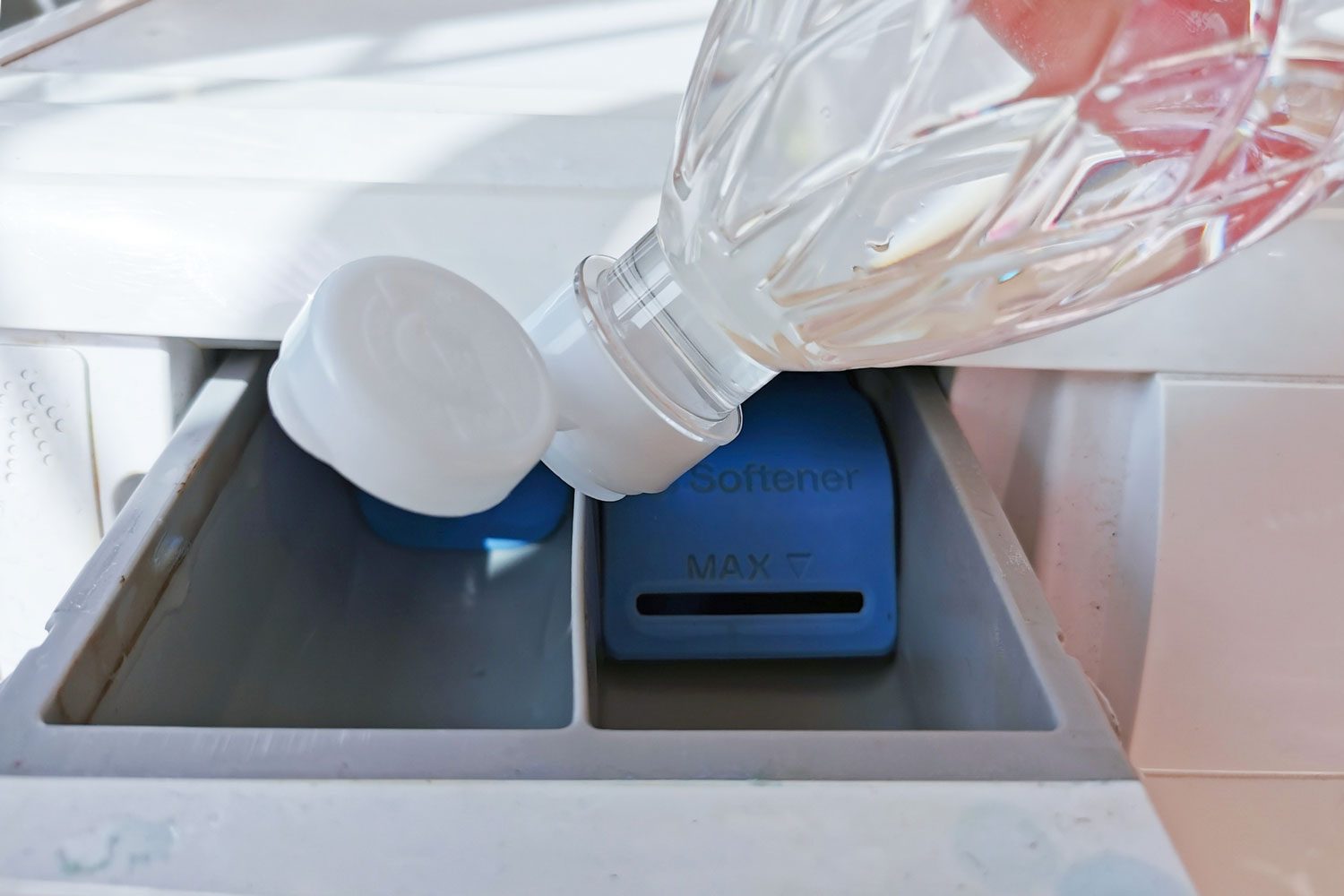 Close Up Hand Pouring The Vinegar Into The Front Loading Drawer to Clean A Washing Machine With Vinegar
