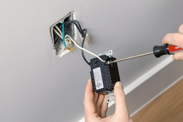 A person fastening the screws with a screwdriver