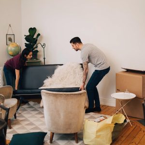 Man and woman arranging sofa in living room