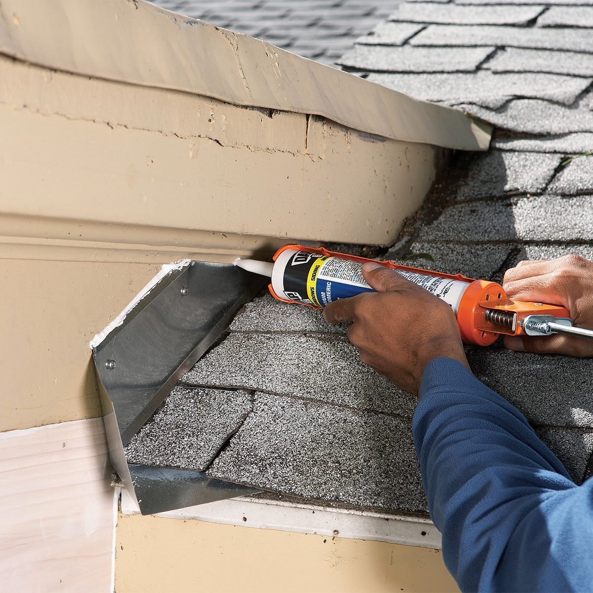 A person using a caulk to seal the roof