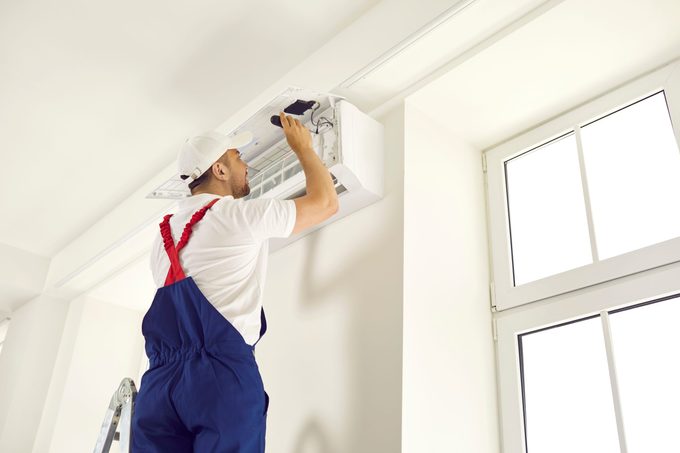 Young,technician,uses,screwdriver,and,opens,up,air,conditioner,unit