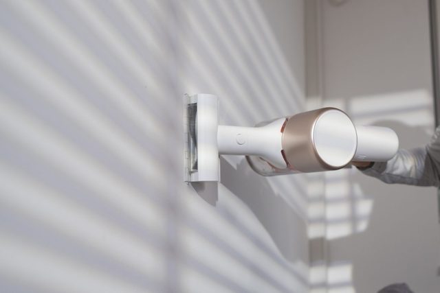 Woman cleaning house with cordless stick vacuum cleaner