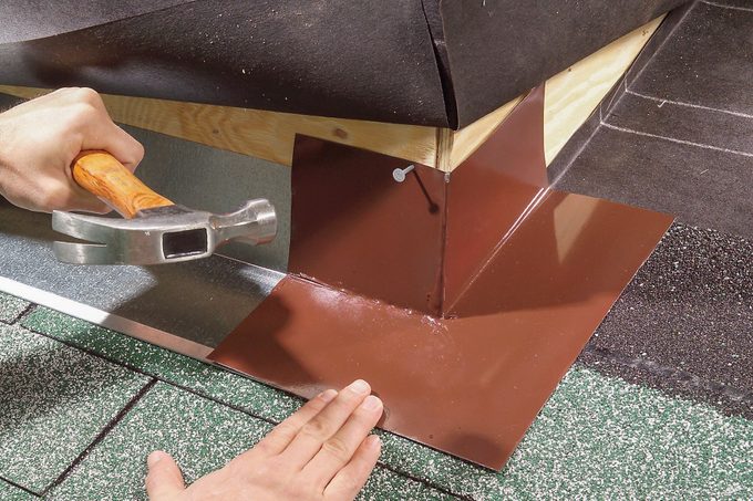 Hands can be seen nailing flashing on base flashing.